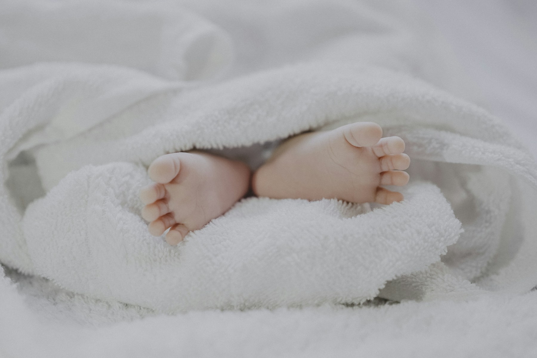 Die Füße eines schlafenden Babys unter einer weichen Decke